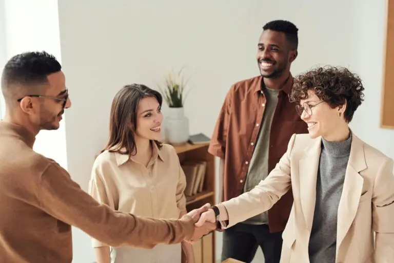 2 hommes 2 femmes, souriants. Un homme donne une poignée de main à une femme, équipe marketing optimisation web